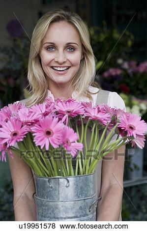 Woman florist or gardener holding a large pot of pink asters View Large Photo Image Stock Photo - Woman florist or gardener holding a large pot of pink asters. Fotosearch
