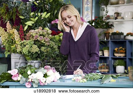 Stock Photo - Woman florist taking an order over the telephone. Fotosearch