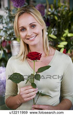 Woman in florist's shop, holding a single red rose View Large Photo Image Stock Photo - Woman in florist's shop, holding a single red rose. Fotosearch