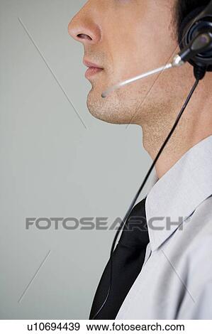 Stock Photo - Portrait of a man using a call centre headset. Fotosearch