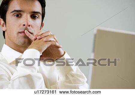 Stock Image - Portrait of a man with a laptop computer, looking pensive. Fotosearch