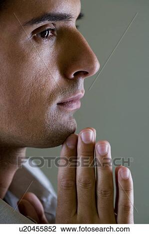 Stock Image - Portrait of a man with his hands in a praying position . Fotosearch