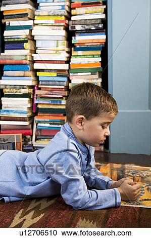 Stock Image - boy looking at picture book on the floor. Fotosearch