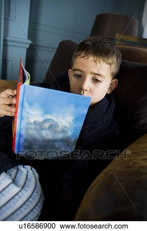 Stock Image - boy reading book in his pajamas. Fotosearch