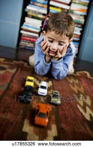 Stock Photograph - little boy playing with toy cars on the floor. Fotosearch