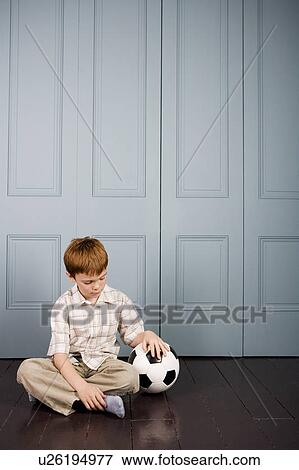 little boy sitting on the floor with football View Large Photo Image Stock Photo - little boy sitting on the floor with football. Fotosearch