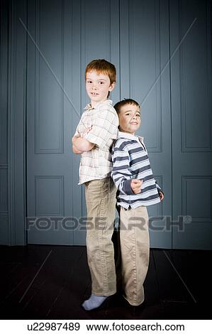 Stock Photo - Older and younger boy standing back to back. Fotosearch