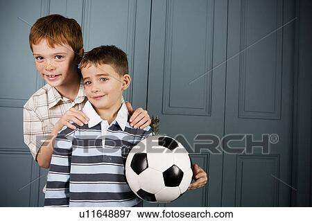 Stock Photo - older boy standing behind younger boy hands on shoulders. Fotosearch