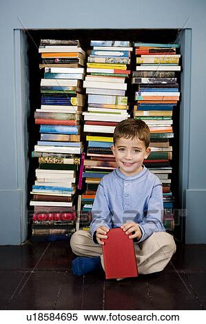 Stock Photography - portrait little boy sitting in front of bookshelf. Fotosearch