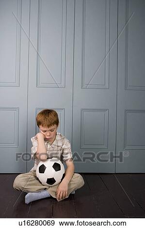 sad little boy sitting on floor with football View Large Photo Image Stock Photo - sad little boy sitting on floor with football. Fotosearch