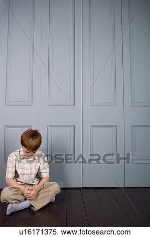 Stock Photography - unhappy little boy sitting on the floor. Fotosearch