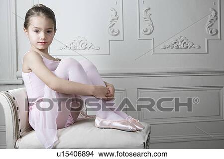 Picture - Young girl in a tutu and ballet shoes sitting on a chair. Fotosearch