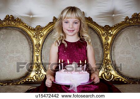 Stock Image - Little girl holding a birthday cake with lit candles. Fotosearch