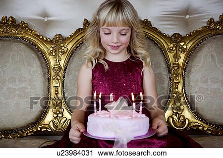 Stock Image - Little girl holding a birthday cake with lit candles. Fotosearch