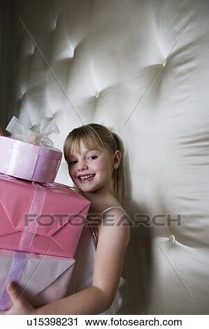 Stock Image - Little girl holding a stack of presents . Fotosearch