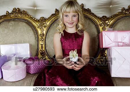 Stock Image - Little girl holding out a birthday present . Fotosearch