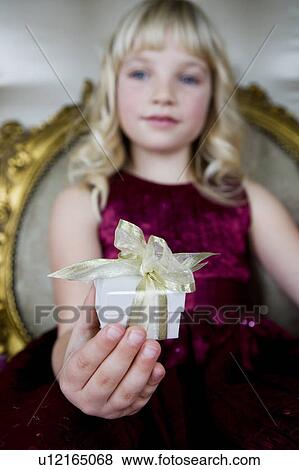 Stock Photo - Little girl holding out a birthday present . Fotosearch