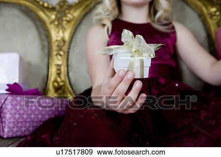 Stock Photo - Little girl holding out a birthday present . Fotosearch