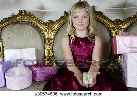 Stock Photograph - Little girl holding out a birthday present . Fotosearch
