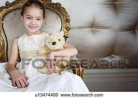 Little girl sitting in an ornate chair wearing a party dress holding a teddy bear View Large Photo Image Stock Photo - Little girl sitting in an ornate chair wearing a party dress holding a teddy bear. Fotosearch