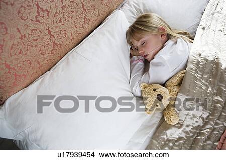 Picture - Young girl asleep in her bed with a teddy bear . Fotosearch