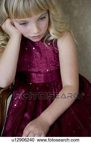 Stock Image - Young girl in a party dress looking bored and unhappy. Fotosearch