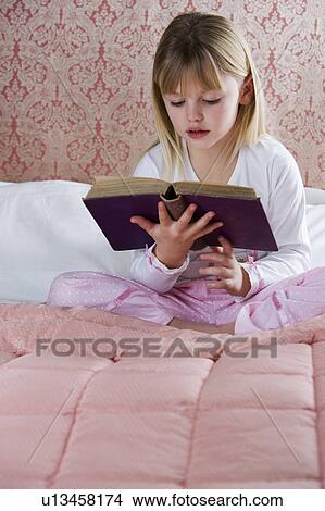 Young girl in her bedroom reading a book View Large Photo Image Picture - Young girl in her bedroom reading a book . Fotosearch