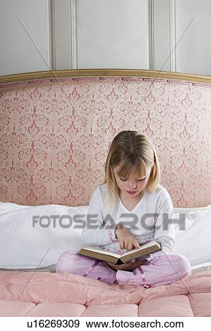 Stock Photo - Young girl in her bedroom reading a book . Fotosearch