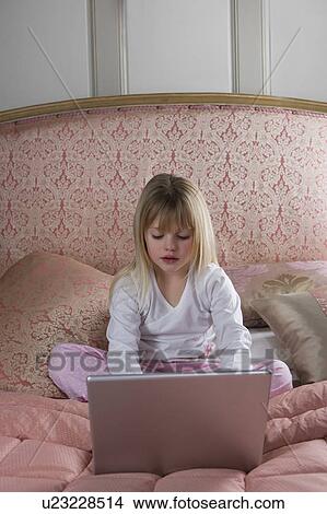 Young girl using a laptop computer in her bedroom View Large Photo Image Picture - Young girl using a laptop computer in her bedroom . Fotosearch
