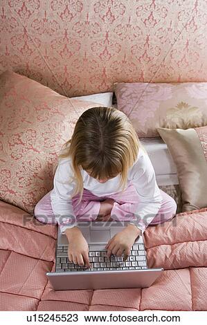 Young girl using a laptop computer in her bedroom View Large Photo Image Stock Image - Young girl using a laptop computer in her bedroom . Fotosearch