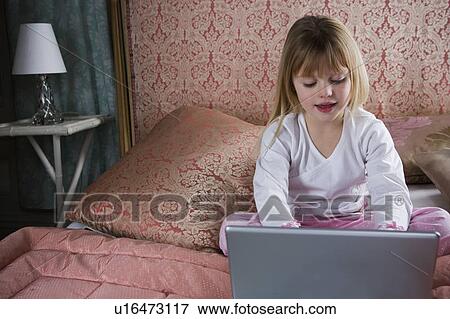 Young girl using a laptop computer in her bedroom View Large Photo Image Stock Photo - Young girl using a laptop computer in her bedroom . Fotosearch