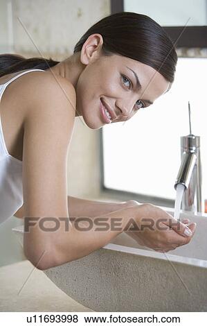 Stock Photo - A woman washing at a sink. Fotosearch