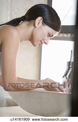 Stock Photo - A woman washing at a sink. Fotosearch