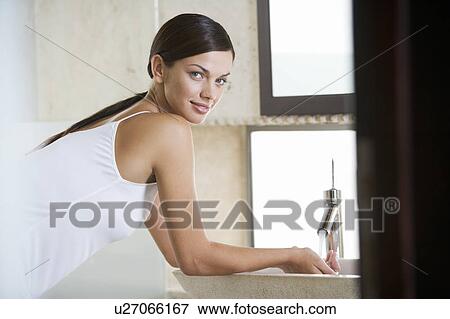 Stock Photo - A woman washing at a sink. Fotosearch