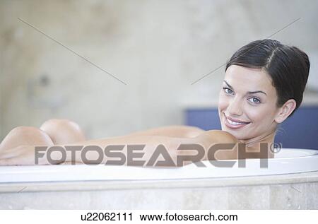 Stock Image - A young woman laying in a bath. Fotosearch