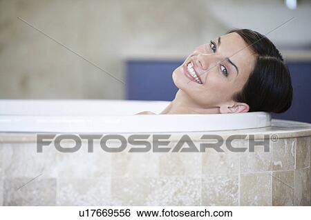 Stock Photograph - A young woman laying in a bath. Fotosearch