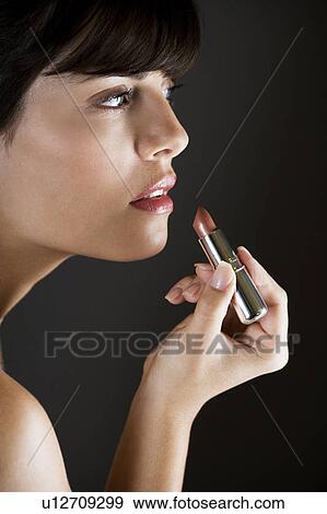 Woman applying lipstick View Large Photo Image Stock Photo - Woman applying lipstick. Fotosearch