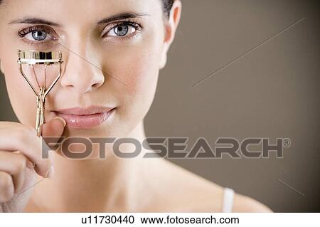 Stock Image - Woman curling her eyelashes. Fotosearch
