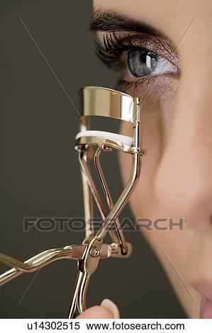 Woman curling her eyelashes View Large Photo Image Stock Photography - Woman curling her eyelashes. Fotosearch