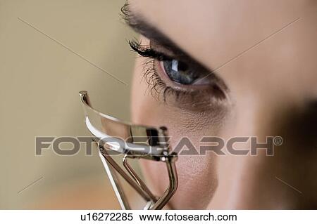 Stock Photography - Woman curling her eyelashes. Fotosearch
