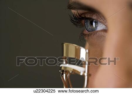Stock Photography - Woman curling her eyelashes. Fotosearch