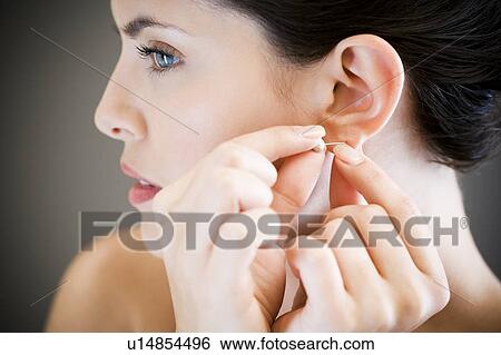 Woman putting in earrings View Large Photo Image Stock Photograph - Woman putting in earrings. Fotosearch