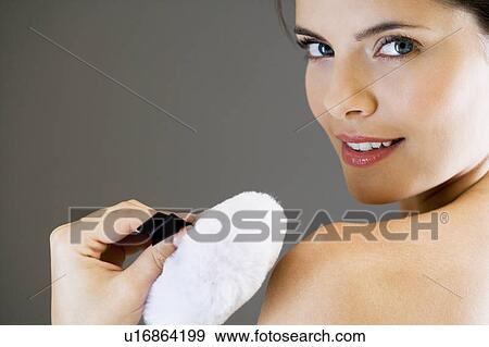 Woman putting powder on her skin with a powder puff View Large Photo Image Stock Photo - Woman putting powder on her skin with a powder puff. Fotosearch