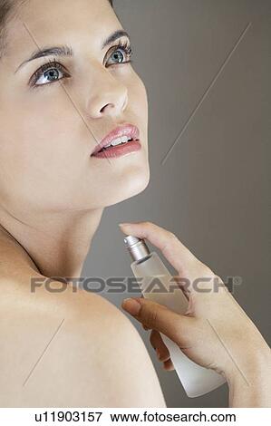 Stock Photo - Woman spraying perfume onto her neck. Fotosearch