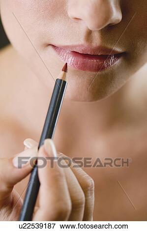 Woman using a lip pencil View Large Photo Image Stock Photo - Woman using a lip pencil. Fotosearch