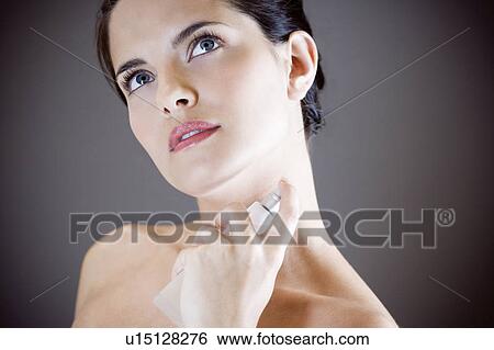 Young woman spraying perfume on her neck View Large Photo Image Stock Photograph - Young woman spraying perfume on her neck. Fotosearch