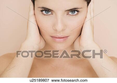 Stock Photo - Portrait of young woman holding her hands beside her face. Fotosearch