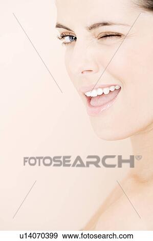 Stock Photo - Portrait of young woman winking to camera. Fotosearch