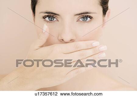 Stock Image - Young woman with hand over her mouth, speak no evil. Fotosearch
