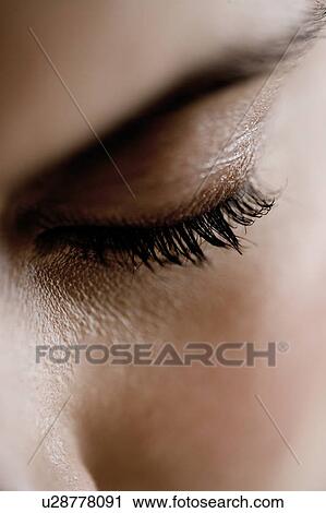 Stock Image - Detail of woman's face showing left eye, looking down. Fotosearch